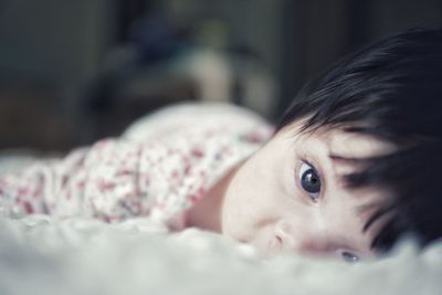 Close-up of cute baby girl lying down on bed