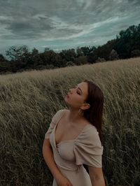 Beautiful woman standing on field against sky