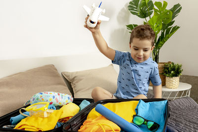 Little caucasian boy with blue shirt ready for vacation. happy child packs clothes into a suitcase