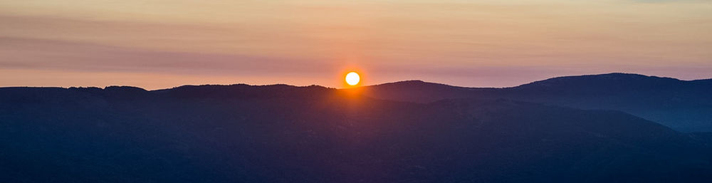 Scenic view of silhouette mountains against romantic sky at sunset