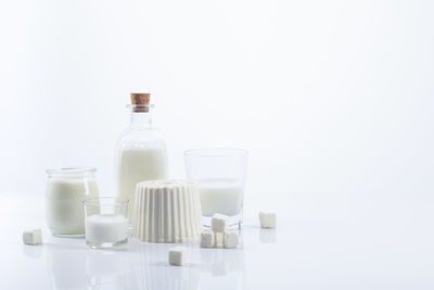 White dairy products in glass recipients on white background with copy space.