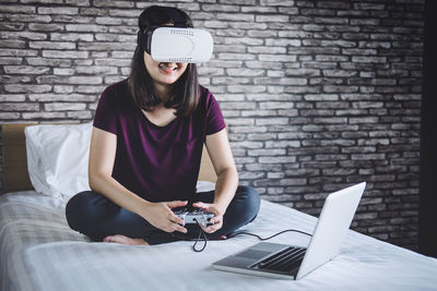 Full length of woman virtual reality simulator while playing video game on laptop at home