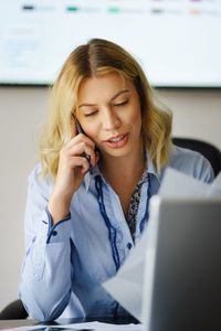 Young woman using phone while sitting on table