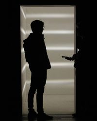 Rear view of silhouette man standing against door at home