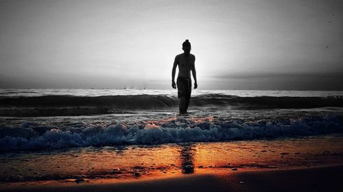 Silhouette man standing at beach against clear sky