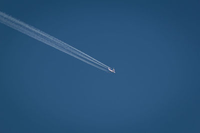Low angle view of airplane flying against clear blue sky