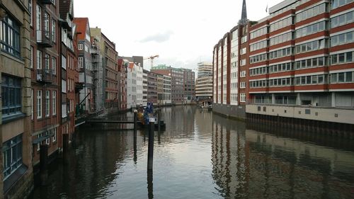 Canal in city against sky