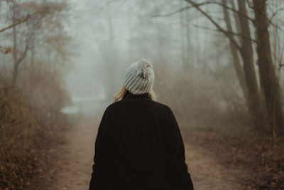 Rear view of woman in forest during winter