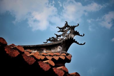 Low angle view of statue on roof against sky