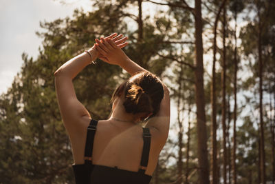 Midsection of woman standing by tree in forest