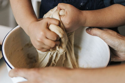 Daughter helping mother in preparing cinnamon rolls dough at home