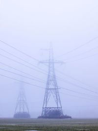 Electricity pylon on field against sky