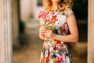 Midsection of woman holding red standing against blurred background