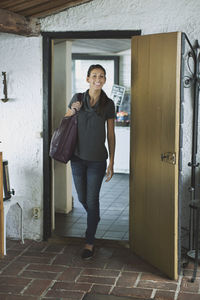 Full length of happy woman entering a house