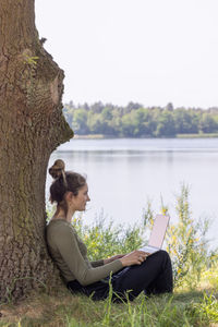 Side view of woman sitting by lake