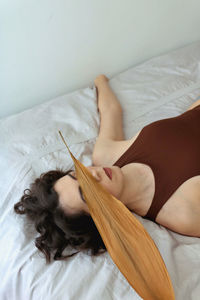 High angle view of woman with leaf lying on bed