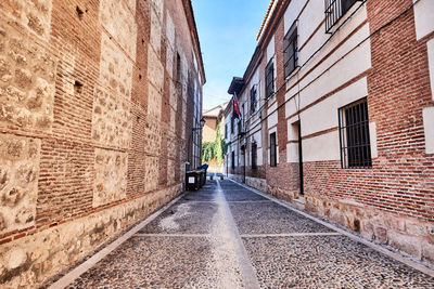 Alley amidst street in city against sky