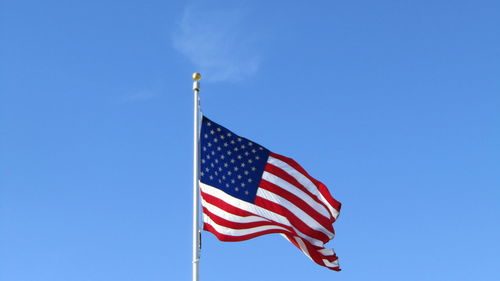 Low angle view of american flag against sky on sunny day