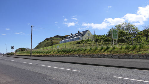 Road by plants in city against sky