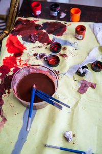 High angle view at artists palettes splattered with paint lying on table lit by sunlight.