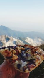 Close-up of hand holding ice cream against mountain range