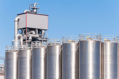 Low angle view of industry against clear blue sky