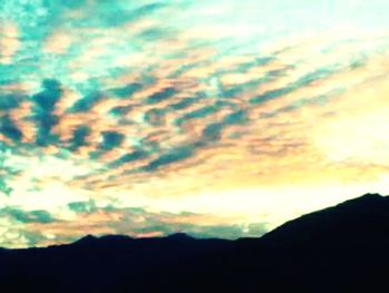 Silhouette of mountain against cloudy sky