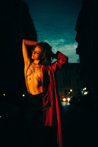 Young woman looking away while standing at night