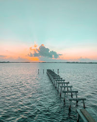 Pier over sea against sky during sunset