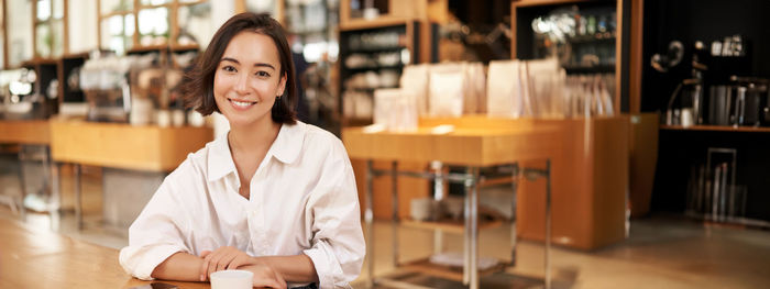 Portrait of smiling young woman standing in library