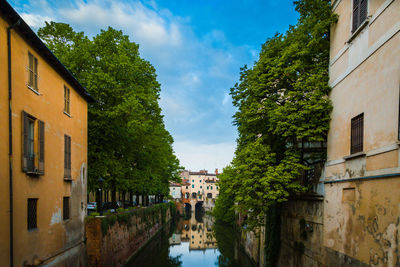 Canal amidst buildings against sky