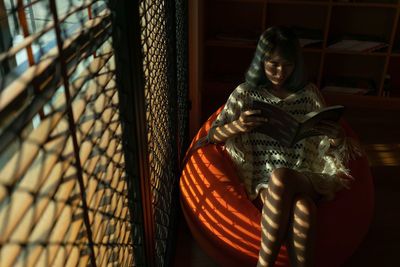 Woman reading book while sitting at home