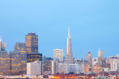 Modern buildings in city against clear blue sky