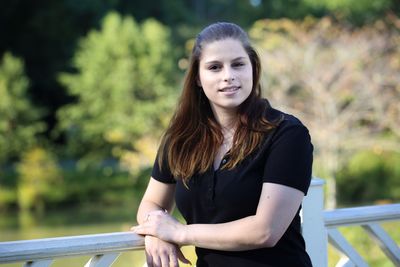 Portrait of smiling young woman standing against trees