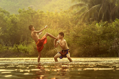 Shirtless boys playing in swamp