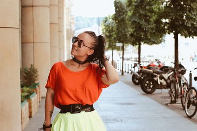 Young woman standing on motorcycle in city