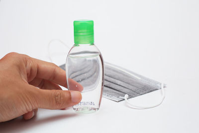 Close-up of hand holding glass against white background