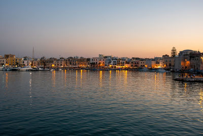 Buildings by river against clear sky