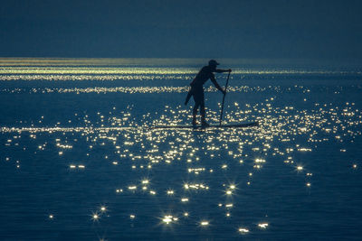 Man standing on surfboard on sea