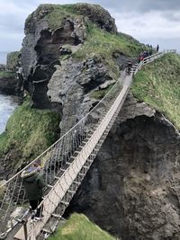 People on footbridge against mountain