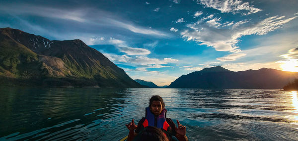 Portrait of man sitting sitting in boat at lake against sky