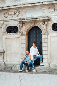 Full length of couple sitting outside building