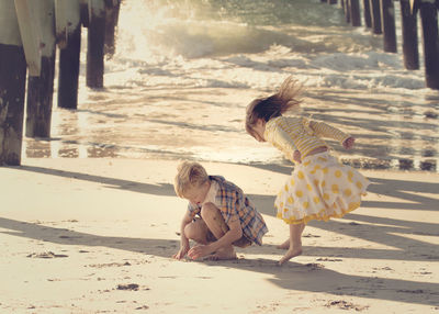 Siblings playing on sand at beach