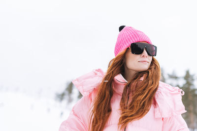 Portrait of young woman standing against snow