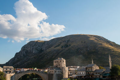 Buildings by mountain against sky