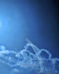 Low angle view of vapor trail against blue sky