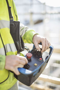 Midsection of worker operating control tool at construction site