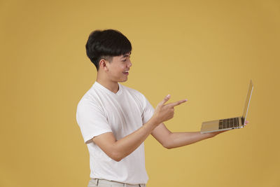 Man using mobile phone against yellow wall