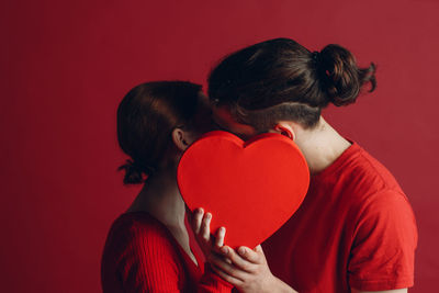 Midsection of couple holding red heart