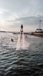 Rear view of man surfing in sea against sky